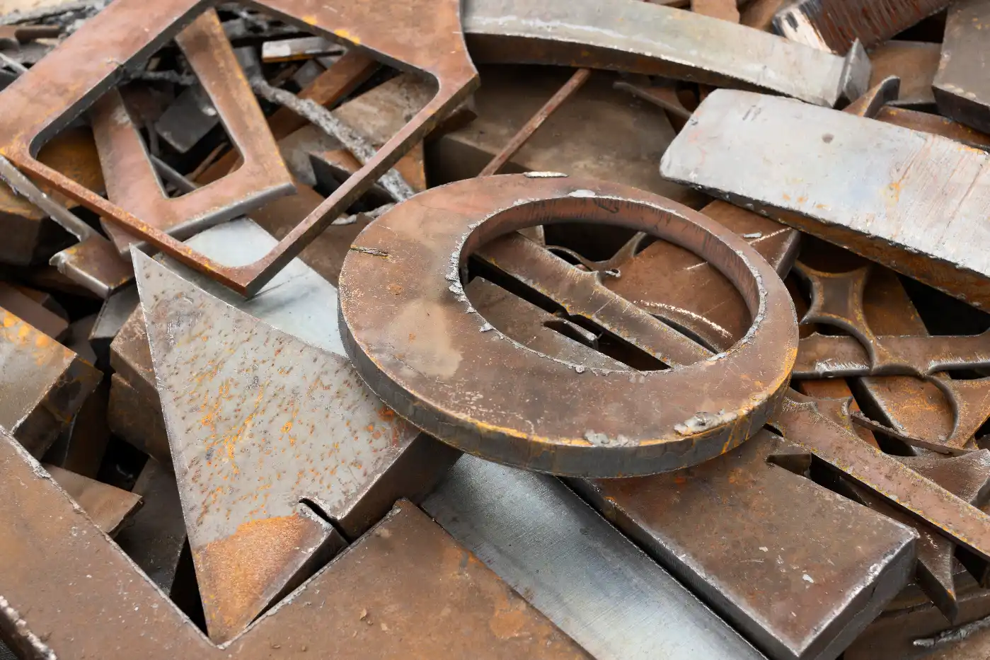 Rusty steel offcuts ready for scrap recycling Pile of rusty steel offcuts, plates and cut-out shapes ready for scrap metal recycling